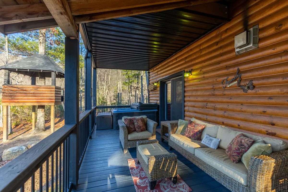 An inviting outdoor seating area featuring a hot tub, wooden play structure, and comfortable seating with decorative cushions. Surrounded by greenery, the space beckons for family relaxation, stargazing, and post-adventure unwinding.